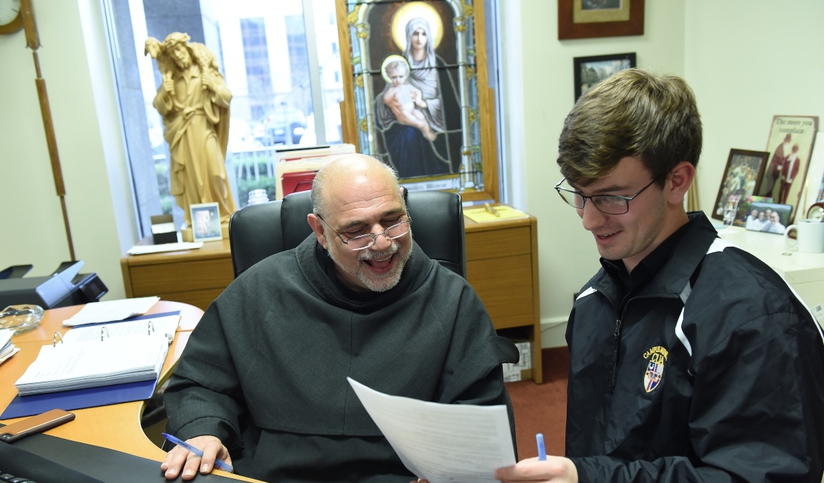 Father Jude, campus chaplain, speaking to a male student